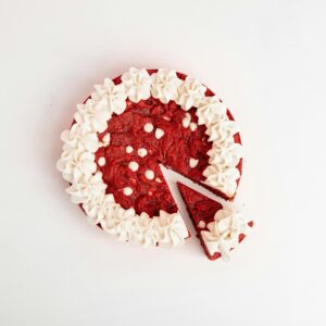 Appetizing red velvet cake with cream frosting on white background. A slice is cut out.
